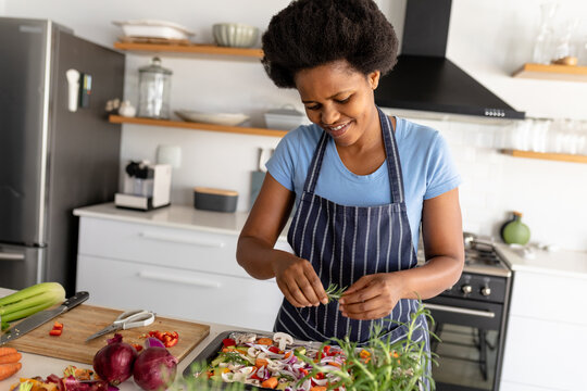 Smling african american mid adult woman preparing food in kitchen at home