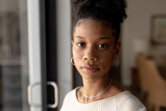 Close-up Portrait Of Serious Confident African American Young Woman By Window At Home