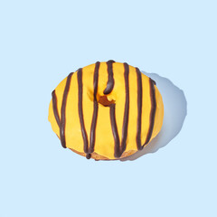 Yellow donut with glaze on blue pastel background