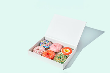 Decorated donuts in a box on light green background