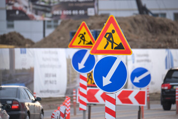 Roadworks warning traffic signs of construction work on city street and slowly moving cars