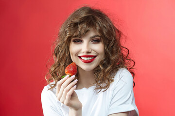 attractive girl with a smile holds a strawberry berry in her hands.