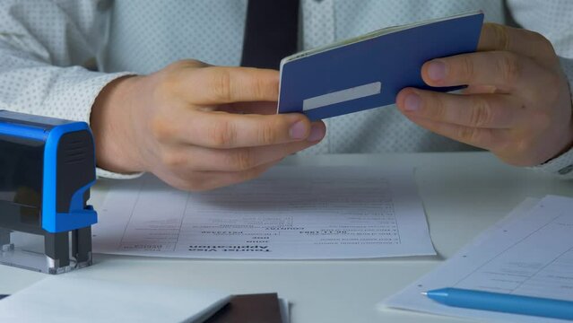 Airport Employee Carries Out Passport Control Of Passenger. Looks At Passport ID And Stamping Visa. Border Agent On Checkpoint. Legal System To Get Permit