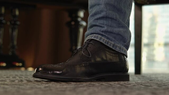the foot beats a rhythm on the floor. The musician taps the melody. Men's leather shoe. Ultra HD