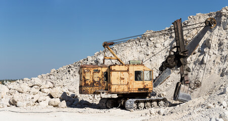 Fototapeta premium Yellow excavator - digging machine for digging and dumping the soil. Work in the quarry.
