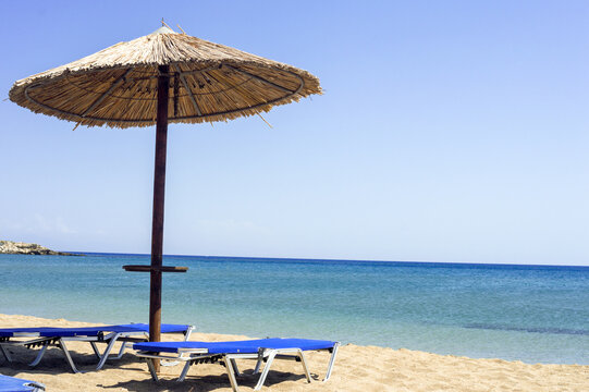 Sun beds under a straw umbrella near the sea on Zephyros beach, Greece