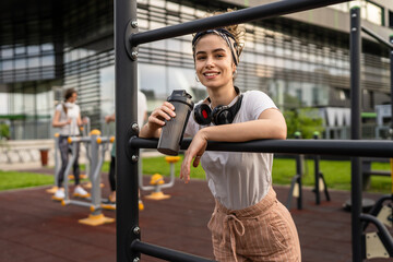 One caucasian woman taking a brake during outdoor training in the park outdoor gym resting on the...