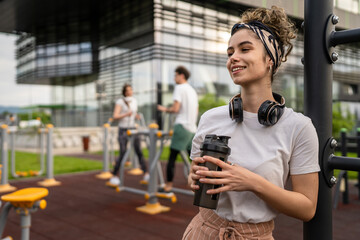 caucasian woman taking a brake during outdoor training in the park outdoor gym resting on the bars...
