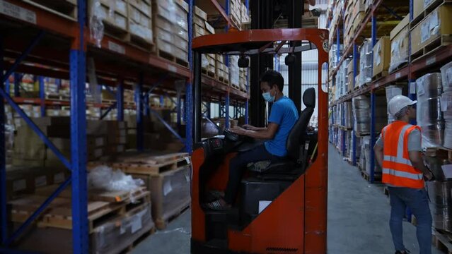 Business concept of 4k Resolution. An employee is driving a forklift in a warehouse.