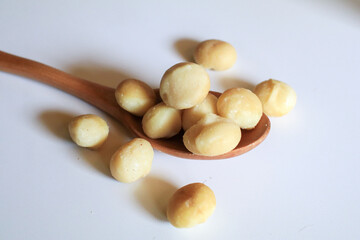 Macadamia nuts in wooden spoon on white background. Healthy product. Macadamia nuts are a source of protein packed with healthy vitamins.