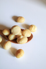 Macadamia nuts in wooden spoon on white background. Healthy product. Macadamia nuts are a source of protein packed with healthy vitamins.