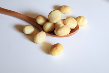Macadamia nuts in wooden spoon on white background. Healthy product. Macadamia nuts are a source of protein packed with healthy vitamins.
