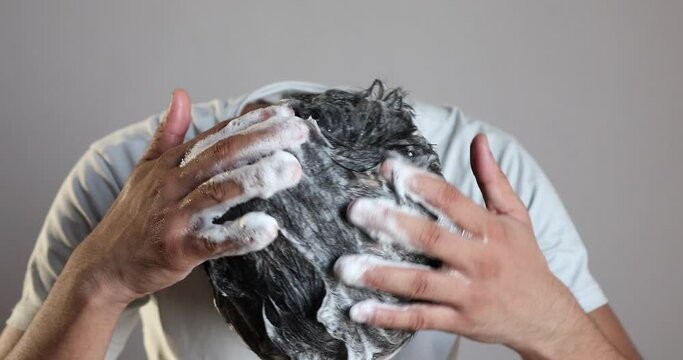 man hand cleaning his hair with a anti dandruff shampoo at home