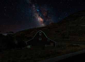 The Milky Way over a barn in the mountains