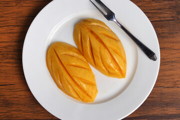 Fresh organic ripe mango fruit on white plate. The fiber, potassium and vitamin content in mangoes...