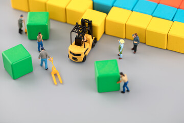Miniature creative laborer carrying building blocks