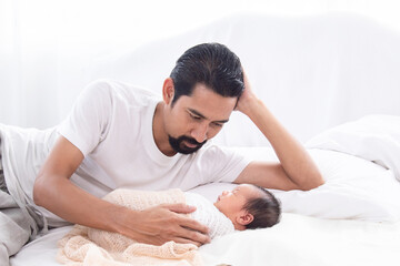 Asian young father looking newborn while baby deeply sleeping with happiness. Little infant wrapped...