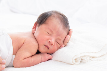 Close up of newborn baby deeply sleeping and mom supports the baby's head tenderly on the white...