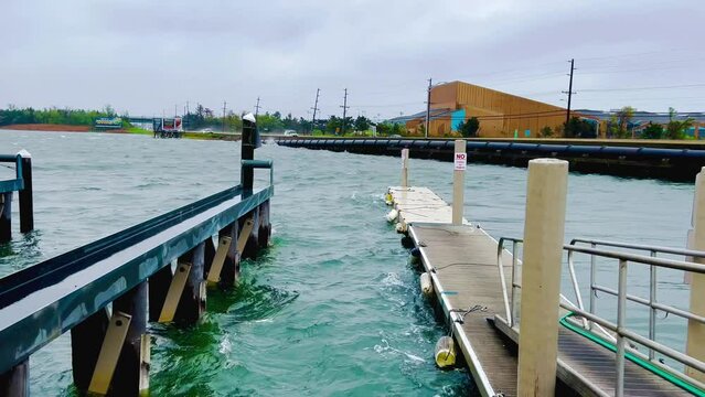 Rough bay water crashes against bulkhead as cars rush by during a storm