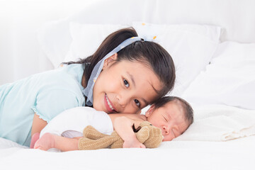 Cute Asian big sister and newborn baby sleep on bed, Girl and adorable infant lying on white bed at...