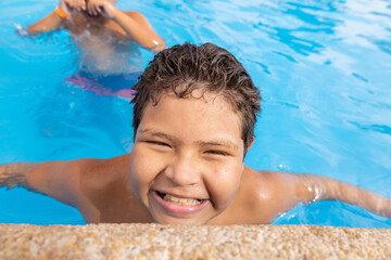 Happy and content boy on summer vacation in the swimming pool smiling
