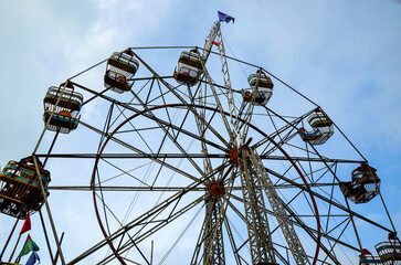Low angle of a tallest ferris wheel, an amusement ride against the blue sky. Zodiac wheel, spinning ride for the amusement in the fair and park
