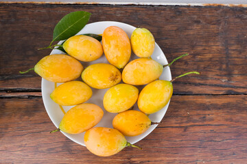 Naklejka na ściany i meble Mayongchid or Plum Mango on wooden table , Sweet yellow Marian plum.