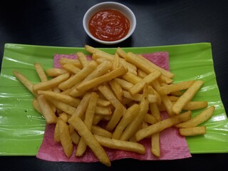 French fries with tomato sauce on a green melamine plate. top view