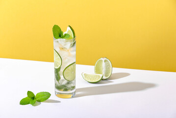 Ice and mojito in a glass lie on the table with a strong shadow - obrazy, fototapety, plakaty
