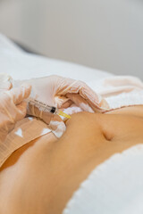Mesotherapy treatment. Beautician applying an injection in the belly of a woman for fat reduction. - obrazy, fototapety, plakaty