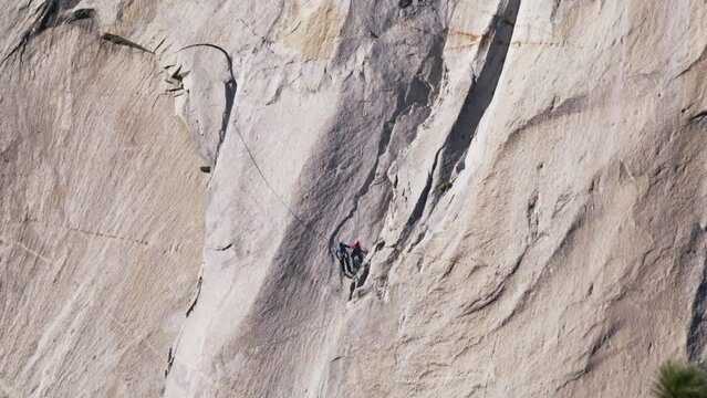 Zoom out RED 6K footage USA tourism. Teamwork helping hand travel silhouette of two strong rock climbers, one male holding another on alpinist rope. Group team tourists lends helping climb mountains