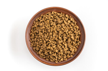 Pet food. Dry pelleted food in a brown clay bowl against a white background. The pellets are triangular in shape.