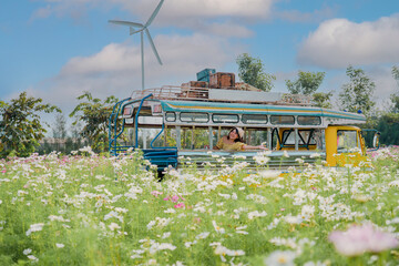 Cheerful pretty young woman with hair tied by handkerchief sitting old truck with her Prairie dog pet in the Blooming flower field country farm with blue sky.