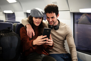 Loving couple travel by train. Happy woman and man talking while sitting in the train.