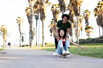 Fototapeta premium Beautiful couple having fun outdoors. Portrait of an excited young couple with skateboard.
