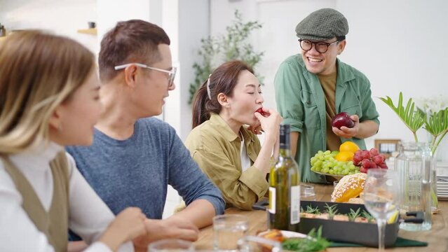 Group of Asian people friends enjoy dinner party eating food and drinking wine on the table with talking together at home. Happy man and woman reunion dinner meeting celebration on holiday vacation