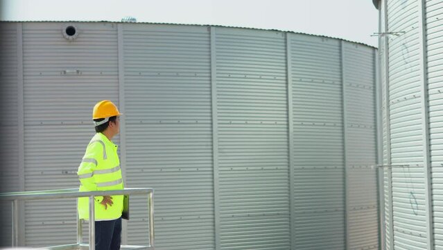 Engineer using laptop examine the construction of water tanks  steel metal sheet for tap water water storage of industrial estate. Utilities of industry.