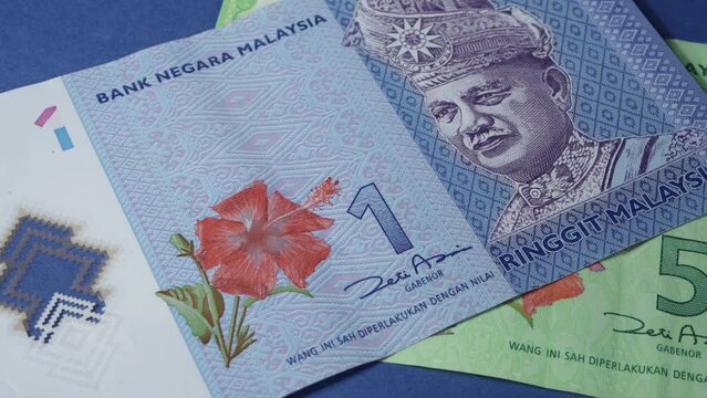 the scrolling of some Malaysia banknotes on a blue surface	