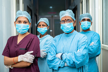 group of surgeons and practitioners confident standing with arms crossed by looking camera at hospital corridor - concept of healthcare and medical service