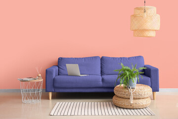 Comfortable sofa and stylish chandelier near pink wall