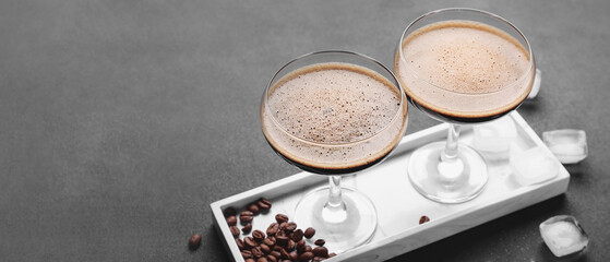 Two glasses of tasty espresso martini cocktail on grey table