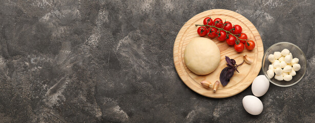 Raw dough and ingredients for pizza on grunge background with space for text