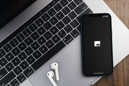 XP Investimentos app on the smartphone screen on wooden background. Office environment. Rio de Janeiro, RJ, Brazil. May 2022