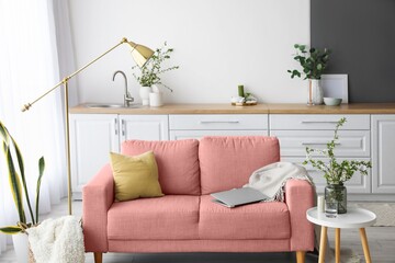 Pink sofa, lamp and table in interior of studio apartment