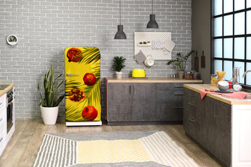 Yellow refrigerator with print of tropical leaves and pomegranates in interior of modern kitchen