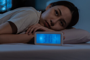 Young Asian woman suffer from insomnia can't sleep at night awaken from stress mental health problem or migraine. Young people health care psychiatry concept. Woman lying on bed can't sleep at night.