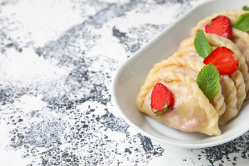 Bowl with tasty strawberry dumplings on grunge background, closeup