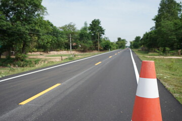 Red rubber cones are placed in the paved road.