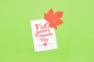 Maple leaf and paper card with text 1ST JULY HAPPY CANADA DAY on green background