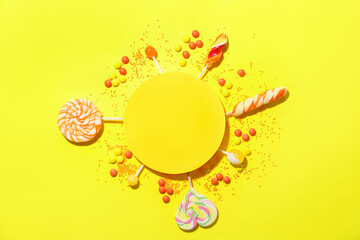 Composition with blank card, lollipops and candies on yellow background